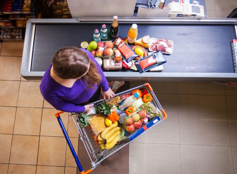 une femme dépose ses courses sur le tapis de caisse au supermarché