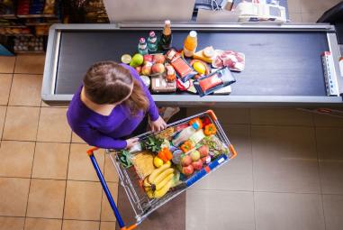 une femme dépose ses courses sur le tapis de caisse au supermarché